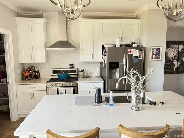 a kitchen with stainless steel appliances kitchen island granite countertop a refrigerator a stove a sink dishwasher and white cabinets with wooden floor