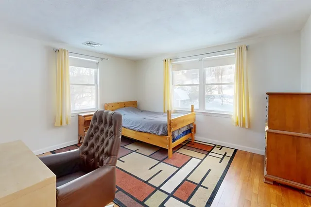 a bedroom with a bed a table and windows