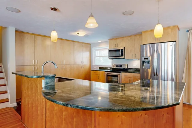 a kitchen with stainless steel appliances granite countertop a refrigerator a sink and a stove