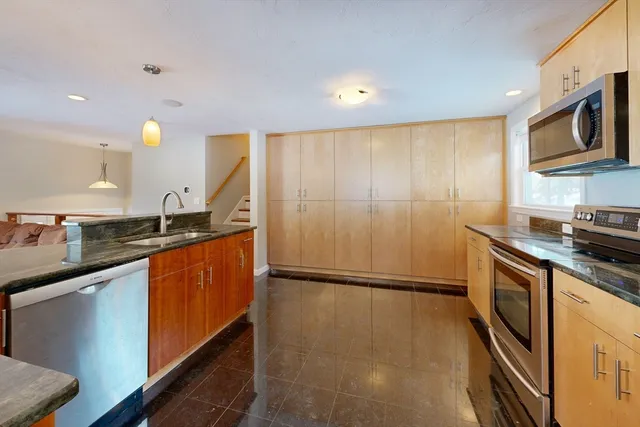 a kitchen with stainless steel appliances granite countertop a sink and a refrigerator