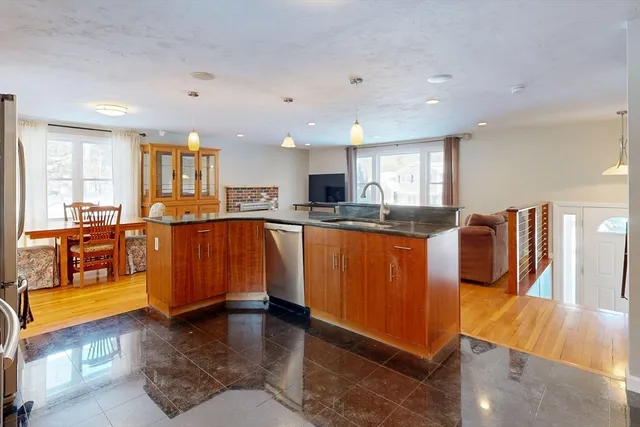 a view of open kitchen with kitchen island stainless steel appliances wooden floor dining table and chairs