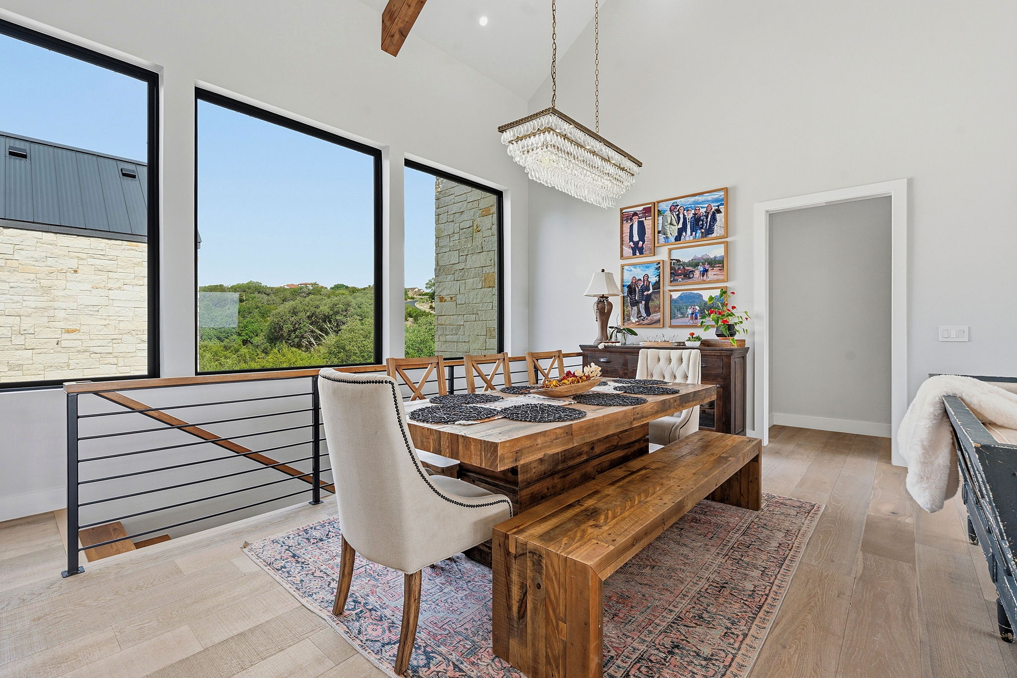 194 Placid Way Spring Branch, TX 78070 - Photo 7 of 37 Dining area featuring a vaulted ceiling with a crystal chandelier, expansive windows, light wood-finish flooring, and a contemporary metal and wood railing