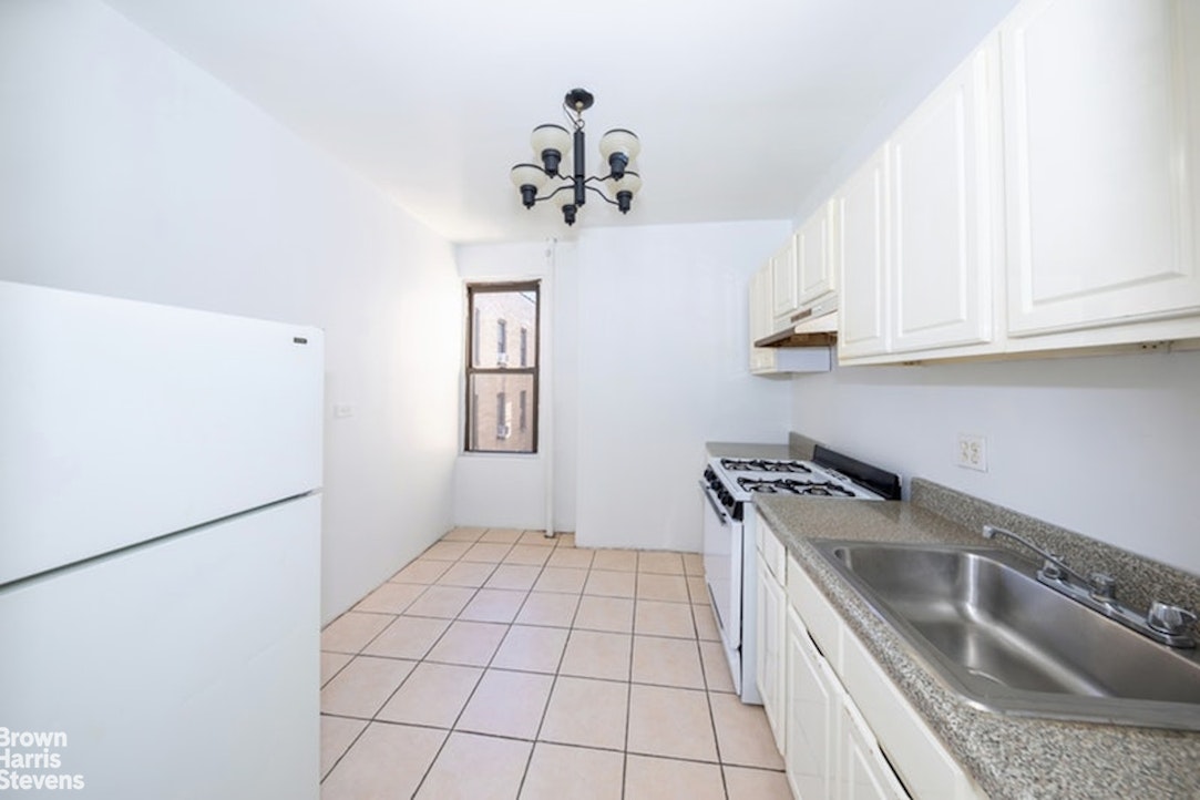 1793 Riverside Drive, Unit 6J Manhattan, NY 10034 - Photo 6 of 7 a kitchen with a sink a stove cabinets and a microwave