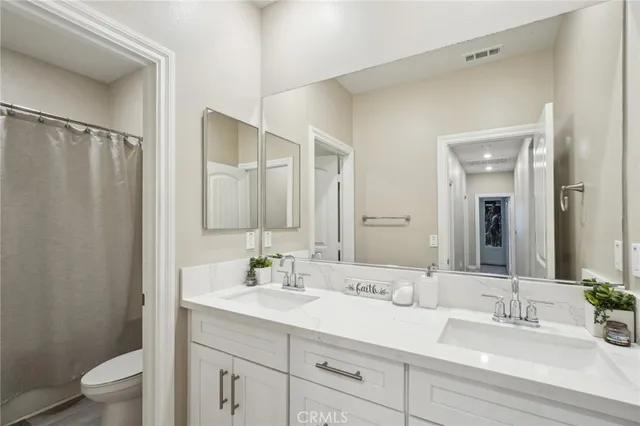 a bathroom with double vanity sink a toilet and a mirror
