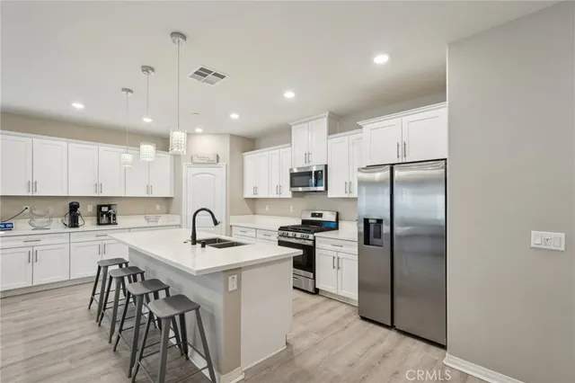 a kitchen with a refrigerator a sink cabinets and wooden floor