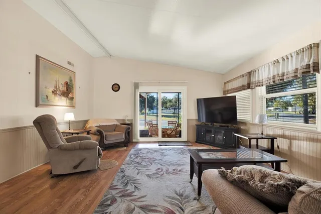 a living room with furniture a flat screen tv and a large window