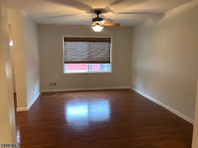 an empty room with wooden floor chandelier fan and windows