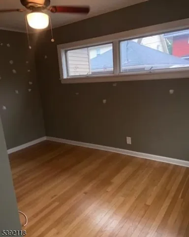 a view of an empty room with wooden floor and windows