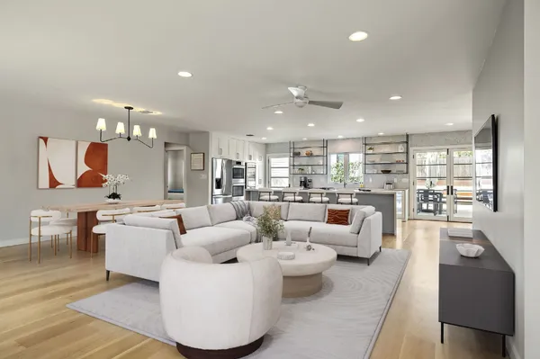 a living room with furniture kitchen view and a wooden floor