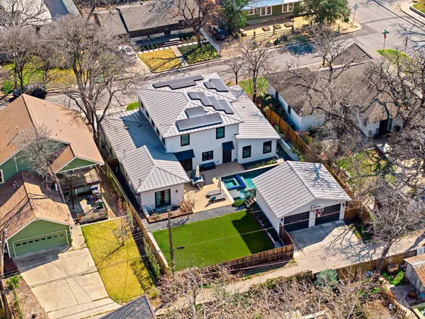 an aerial view of a house with swimming pool and large trees