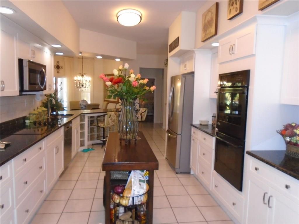 2185 Southeast Harding Street Port St. Lucie, FL 34952 - Photo 13 of 34 a kitchen with stainless steel appliances kitchen island granite countertop a refrigerator and a sink