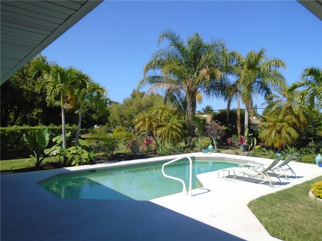 2185 Southeast Harding Street Port St. Lucie, FL 34952 - Photo 2 of 34 a view of a swimming pool with a bench and trees