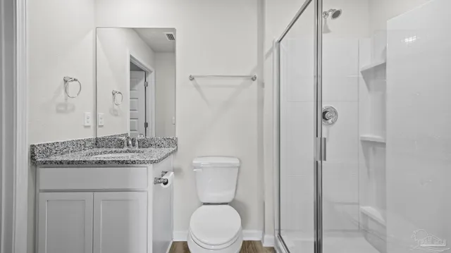 a bathroom with a granite countertop sink toilet a mirror and shower