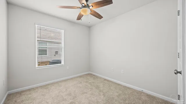 an empty room with a window and a fan