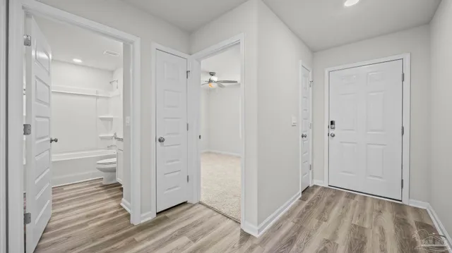 a view of a hallway with wooden floor and a bathroom