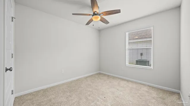 an empty room with a window and a fan