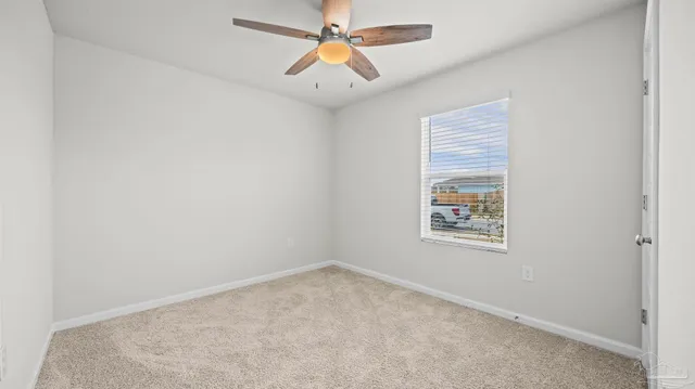 an empty room with windows and fan