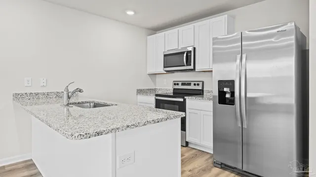 a kitchen with stainless steel appliances granite countertop a refrigerator a stove and a sink