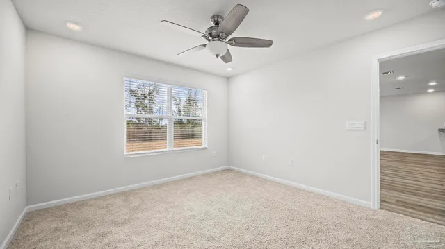 an empty room with a window and a ceiling fan