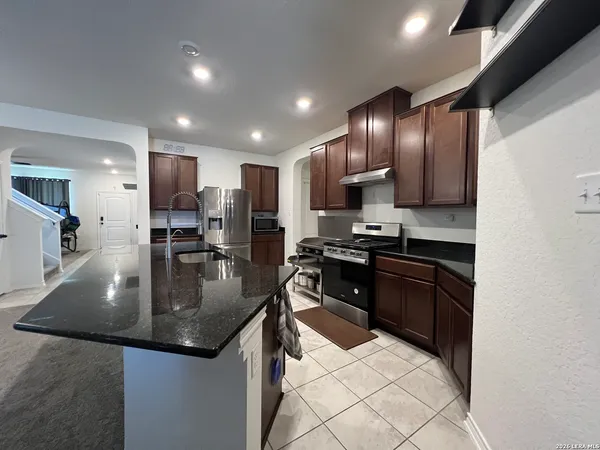 a kitchen with stainless steel appliances granite countertop a stove a sink a refrigerator and a microwave