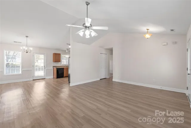 an empty room with wooden floor windows and ceiling fan
