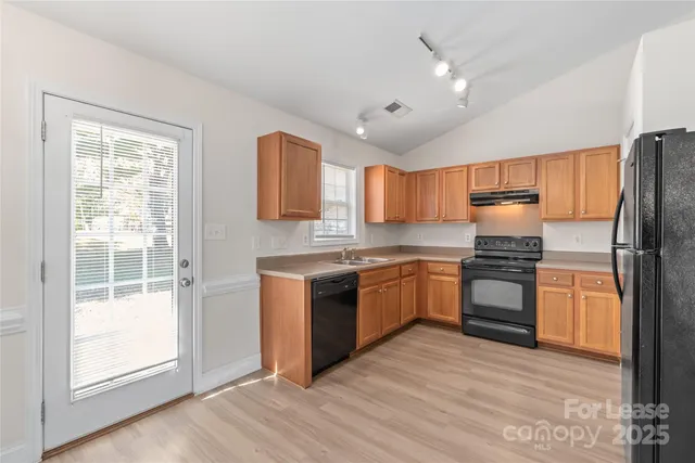 a kitchen with granite countertop stainless steel appliances cabinets a sink and a large window