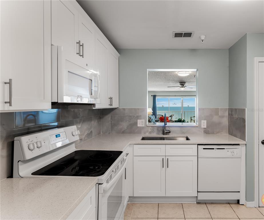 13500 Gulf Boulevard, Unit 602 Madeira Beach, FL 33708 - Photo 15 of 34 a kitchen with white cabinets and white appliances