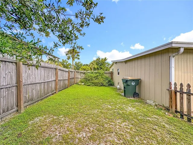 a view of a backyard with wooden fence and large trees