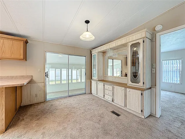 a view of an empty room with window and cabinet area