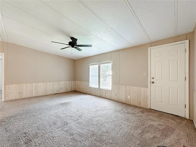 an empty room with a ceiling fan and windows