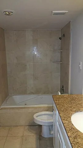 a bathroom with a granite countertop sink a toilet and bathtub