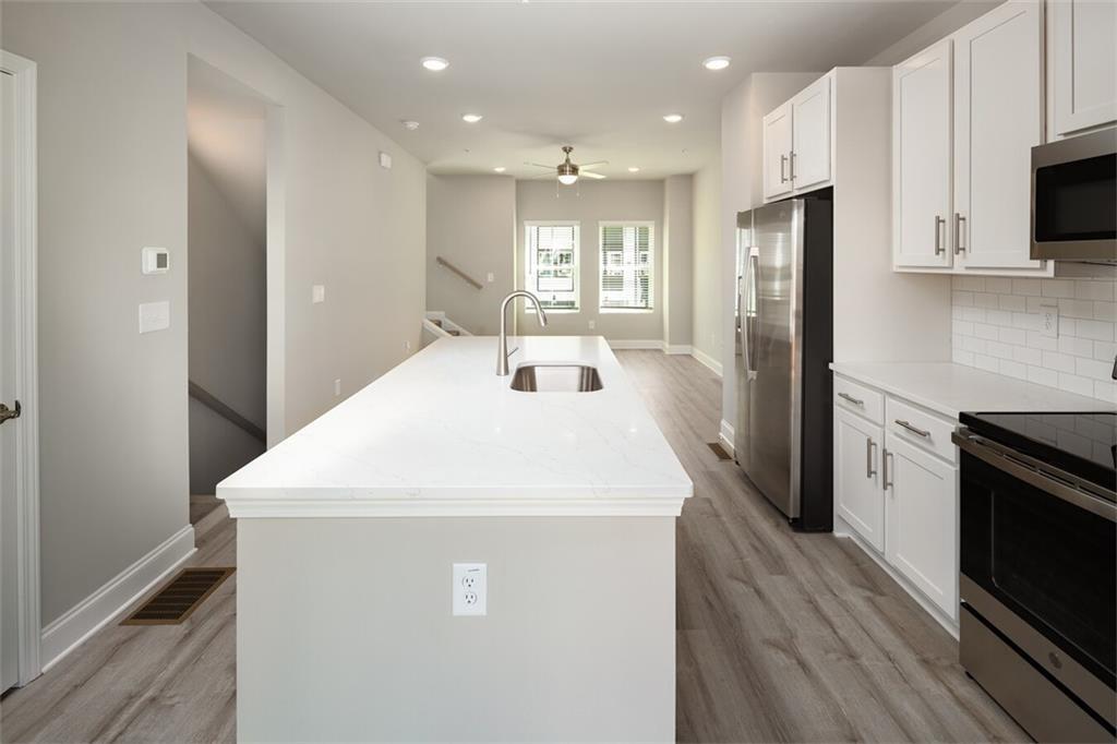 3960 Redan Road, Unit B2 Stone Mountain, GA 30083 - Photo 7 of 23 a kitchen with kitchen island a sink stainless steel appliances and cabinets