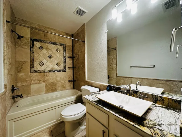 a bathroom with a granite countertop sink toilet and shower