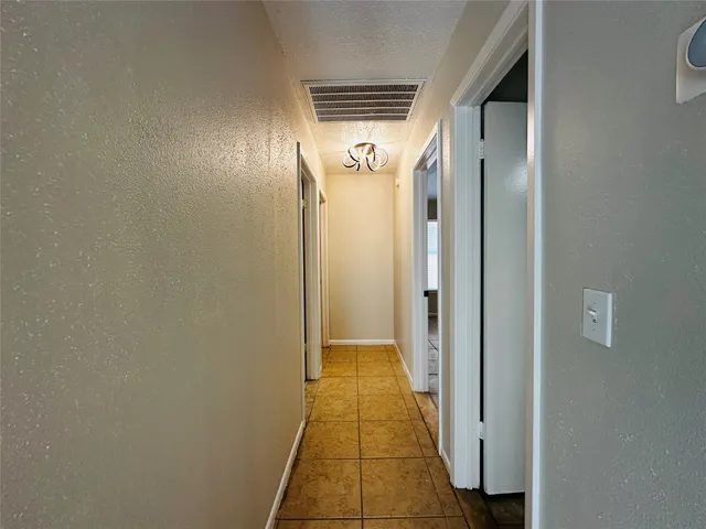 a view of a hallway with wooden floor and a bathroom