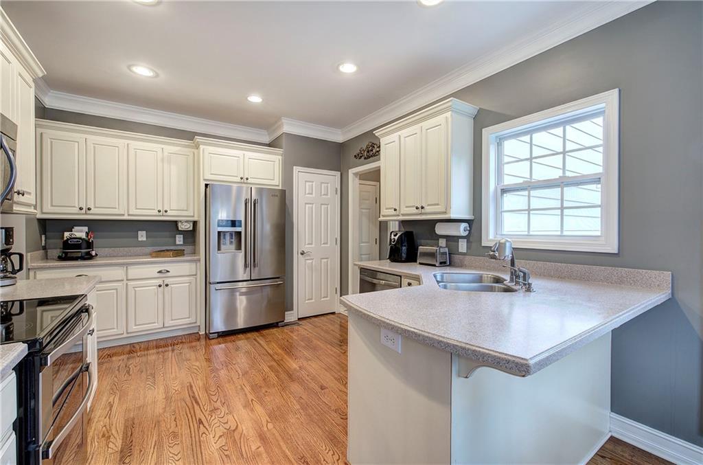 57 Colonial Circle Northwest Cartersville, GA 30120 - Photo 14 of 45 a kitchen with a refrigerator a stove a sink and white cabinets with wooden floor