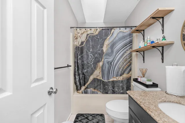 a bathroom with a granite countertop sink a toilet and a mirror