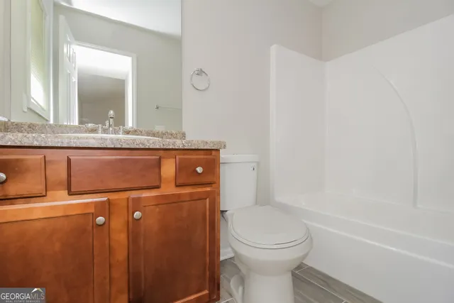 a bathroom with a granite countertop toilet sink and mirror