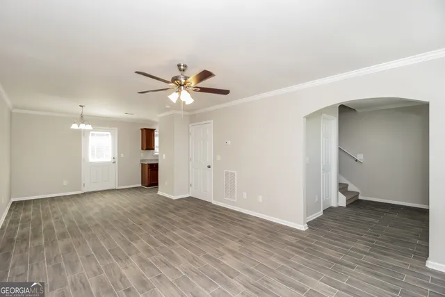 an empty room with wooden floor and a ceiling fan