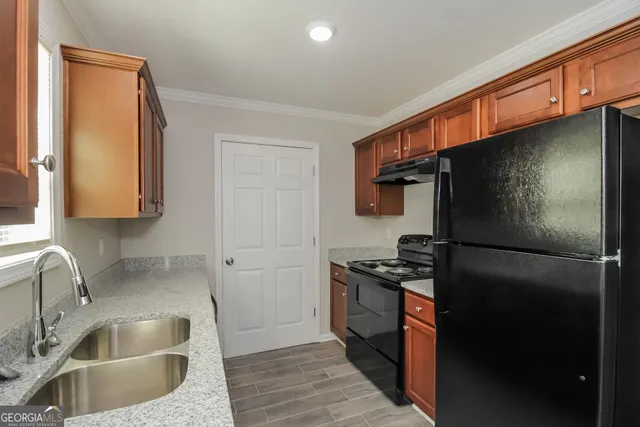 a kitchen with stainless steel appliances granite countertop a refrigerator a sink and a stove