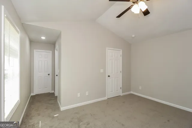 an empty room with a ceiling fan and window