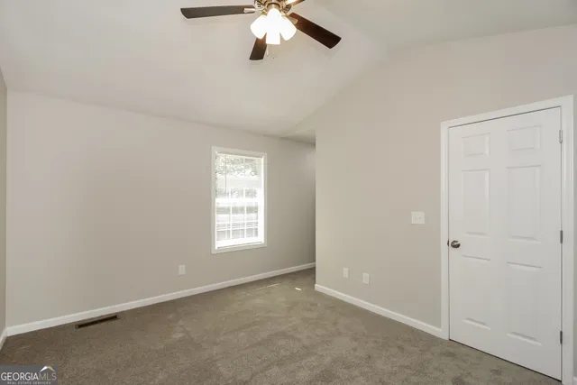 an empty room with a window and a chandelier fan