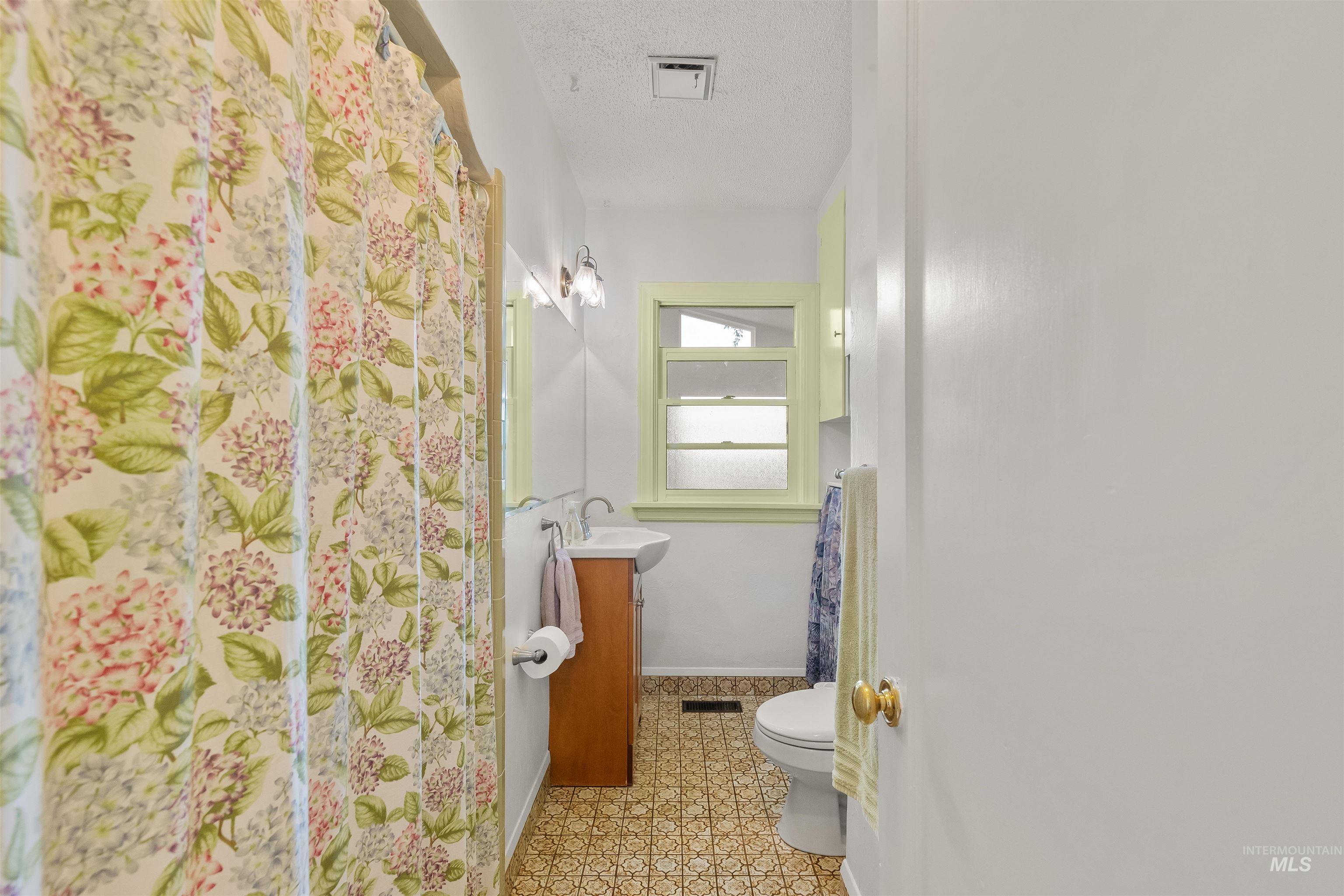 924 N Street Lewiston, ID 83501 - Photo 22 of 46 Bathroom featuring a window with lime green trim, wood vanity with sink, and patterned floor tile