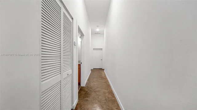 a view of a hallway with wooden floor and a bathroom
