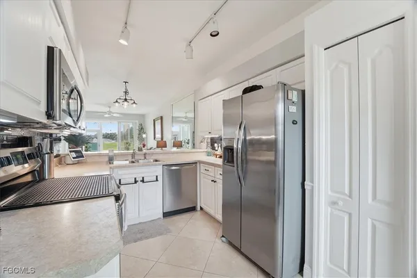 a kitchen with stainless steel appliances granite countertop a refrigerator a sink a stove and a refrigerator