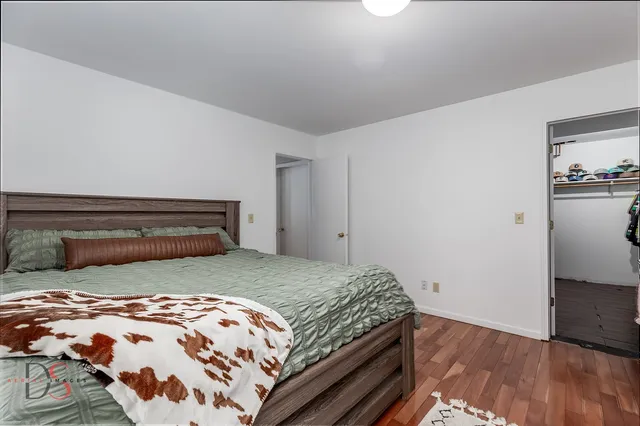 a bedroom with a bed a dresser and wooden floor