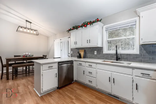 a kitchen with cabinets a sink dishwasher and a stove with wooden floor
