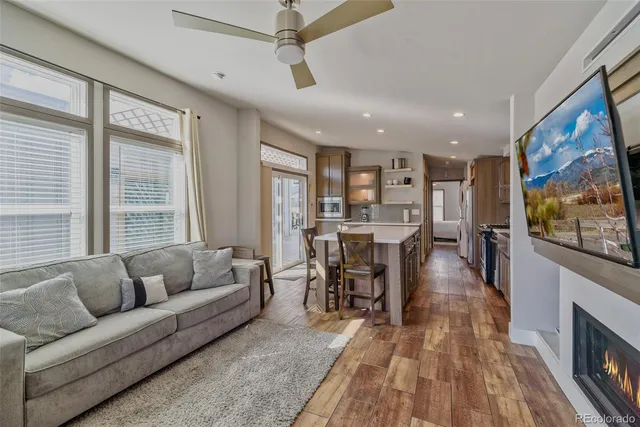 a living room with stainless steel appliances furniture a rug and a kitchen view