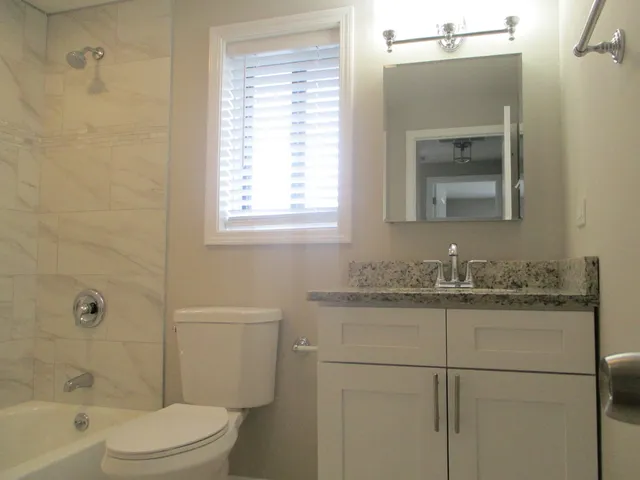 a bathroom with a granite countertop sink toilet a shower and a mirror