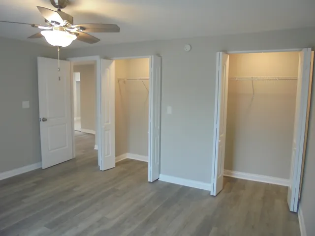 an empty room with wooden floor and ceiling fan