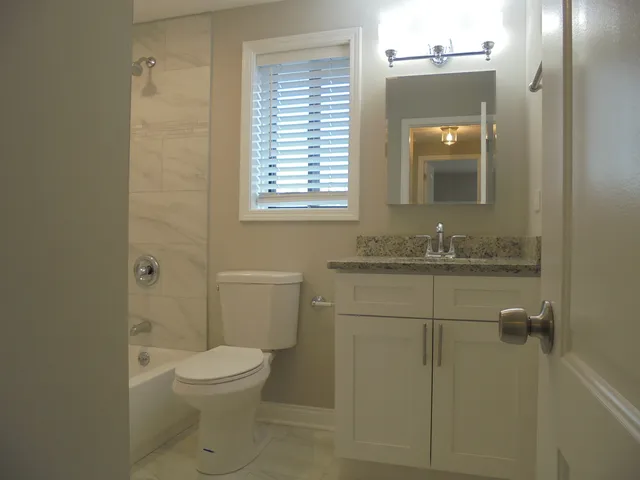 a bathroom with a granite countertop toilet a sink and a mirror